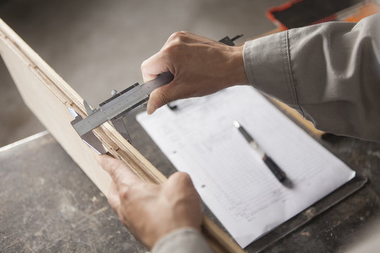 Carpenter measuring wood plank with vernier caliper in factory, Jiangsu, China