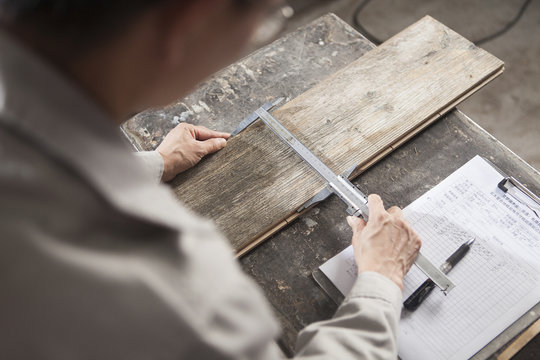 Carpenter measuring wood plank with vernier caliper in factory, Jiangsu, China