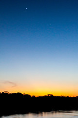 Obraz premium View of a sunset over Amazon river in Brazil. Planets Venus and Jupiter are also visible.