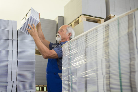 Factory worker moving and stacking cardboard