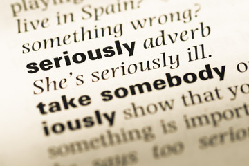 Obraz premium Close up of old English dictionary page with word seriously