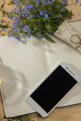 Spring floral bouquet of forget-me, a notebook and a mobile phon