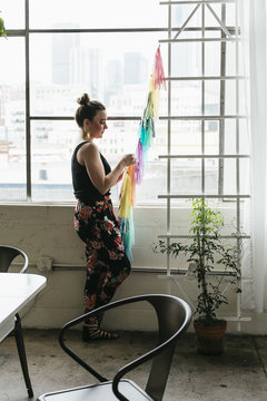 Young female designer making multi colored bunting in design studio