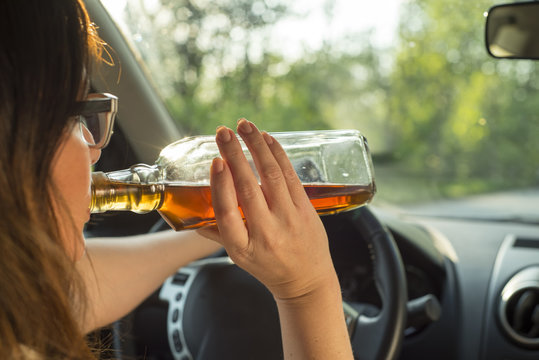 Woman drinking alcohol in the car.