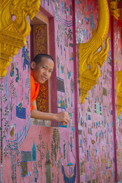 Buddhist monk looking out of Wat Xieng Thong window, Luang Prabang, Laos