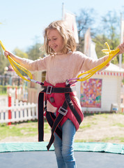Little girl on bungee trampoline with cords.