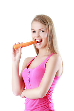 Portrait of a smiling young woman eating a carrot isolated on wh