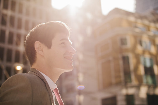 Young city businessman looking up in sunlight