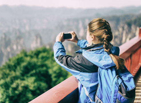 Female tourist taking photo of mountains. Toned image