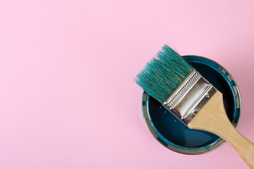 the brush lies on top of the jar of blue paint on a pink background