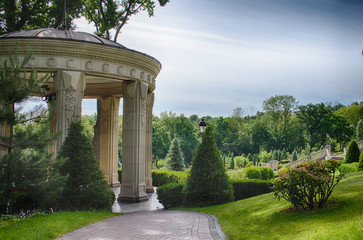 White gazebo in park in early spring. Green park with blue skyline.