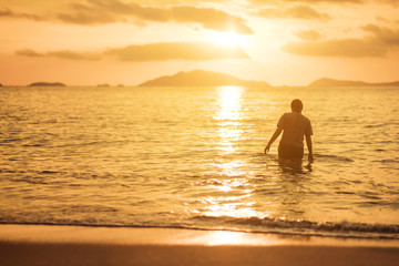 Fototapeta na wymiar Woman walking in the sea in sunset