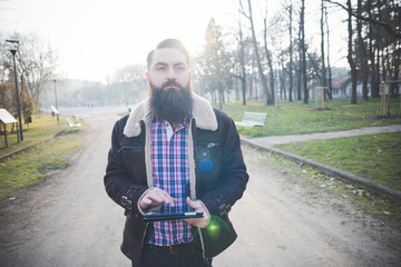 Young bearded man using digital tablet in park