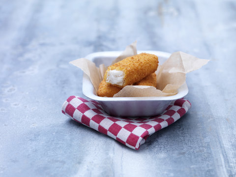 Fried chunky breaded cod fish fingers in baking tin on steel table