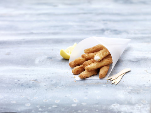 Greaseproof paper cone with lemon sole goujons on steel table