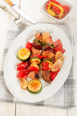 grilled hungarian meat vegetables skewers on an oval plate
