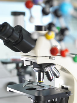 Microscope viewing sample with a ball and stick molecular model illustrating ground breaking research