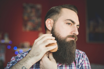 Young bearded man brushing his beard