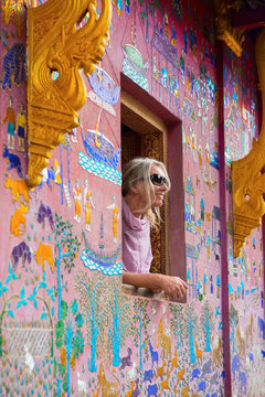 Female tourist looking out of Wat Xieng Thong window, Luang Prabang, Laos