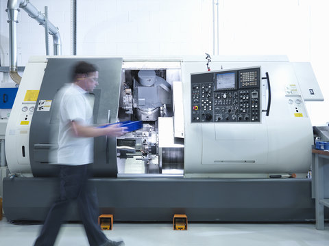 Engineer working with CNC lathe in factory