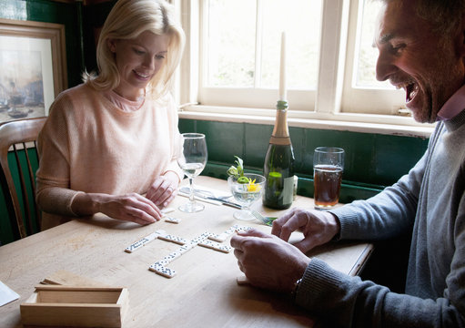 Couple drinking and playing dominoes in pub