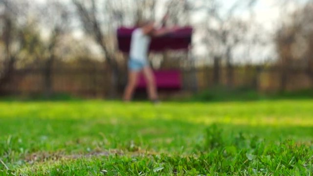 Blurred background: Schoolgirl is doing cartwheel at backyard of summer cottage