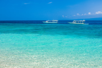 Beautiful beach and tropical turquoise sea with boats on horizon