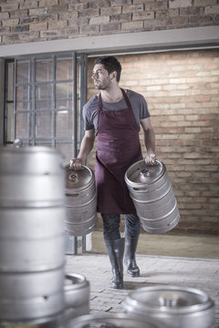 Brewer carrying two kegs of beer