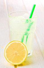 glass of lemonade with straw on wood