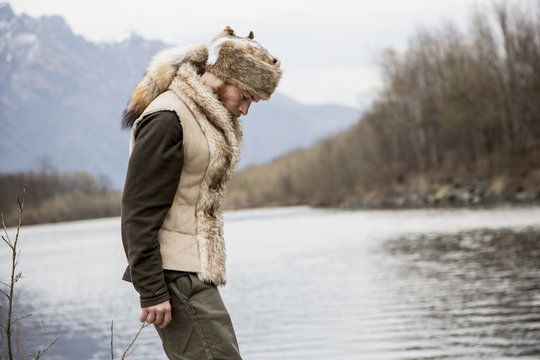 Mid adult man wearing trapper hat by river