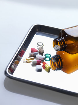 Variety of medical drugs pouring from pill bottle on surgical tray