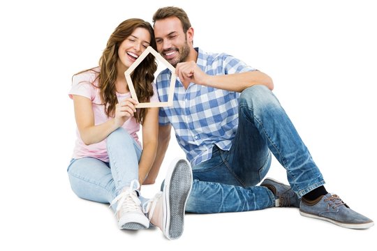 Young couple holding house shaped popsicle sticks