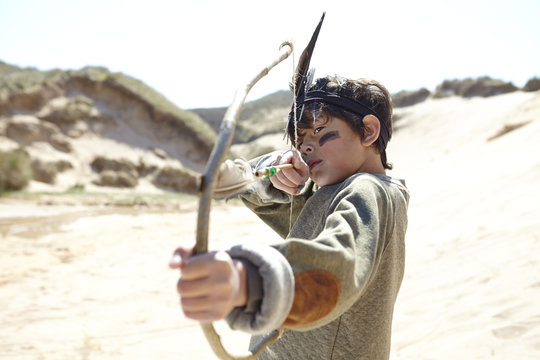 Young boy wearing fancy dress, holding home-made bow and arrow