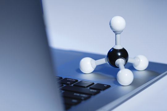 Methane molecule model and a laptop computer. Methane is the simplest hydrocarbon and is a main constituent of natural gas
