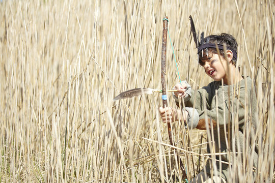 Young boy wearing fancy dress, holding home-made bow and arrow