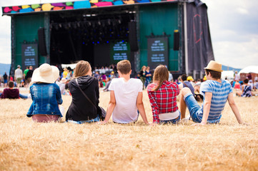 Teenagers, summer music festival, sitting in front of stage - Powered by Adobe