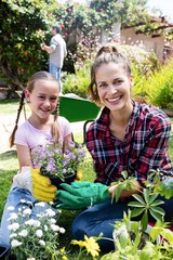 Smiling mother and daughter gardening together in garden