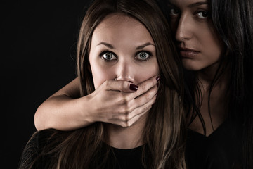 Rivals. Portrait of two women on a black background close-up. One of them frightened. A second...