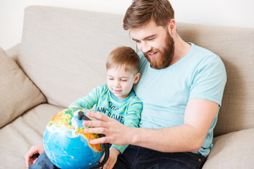 Happy dad and son looking at globe together