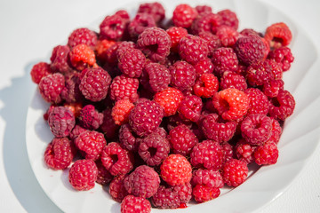 lots of ripe red raspberries on a plate
