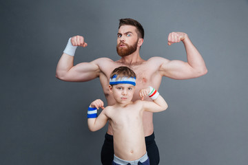 Strong bearded man and his son showing biceps