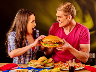 Young couple male and woman eating hamburgers . Fastfood concept.  Very big fast food hamburgers.