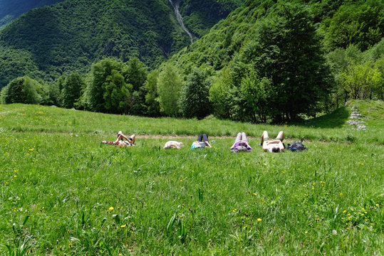 Five mature hikers lying in meadow taking a break