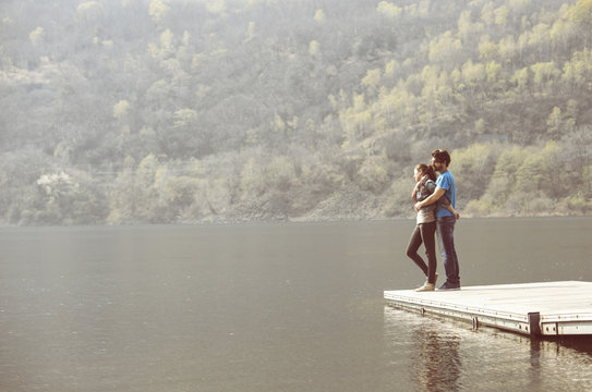 Young couple looking out from pier at Lake Mergozzo, Verbania, Piemonte, Italy