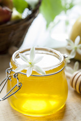 Honey in jar and white flowers on table