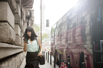 Young businesswoman, using smartphone, outdoors, Shanghai, China