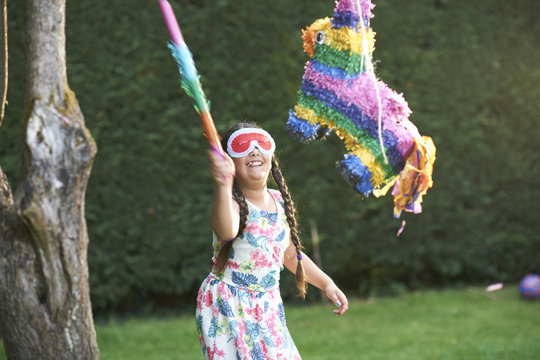 Girl playing pinata in garden