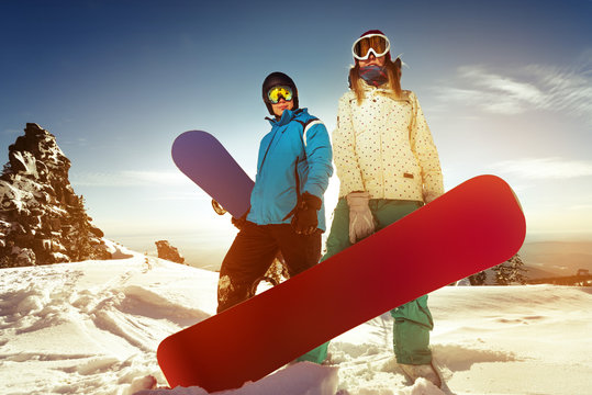 Couple of snowboarders stands in sunset light on mountains top backdrop. Sheregesh resort, Siberia, Russia