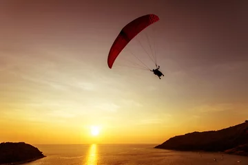 Foto auf Acrylglas Luftsport Silhouette of sky diver flies on background of sunset sky and sea. Phuket island, Thailand