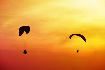 Two skydivers flies on background of sunset sky